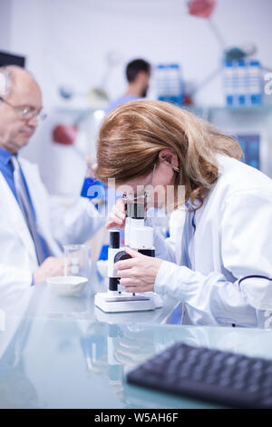 Ingenieurin mit einem weißen Mantel unter dem Mikroskop in einem Labor arbeiten. Moder Labor. Stockfoto