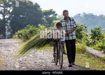 Ein Mann seinen Sohn trägt auf einem Zyklus in der ländlichen Umgebung von Rishikesh, eine heilige Stadt im Bundesstaat Uttarakhand in Indien Stockfoto