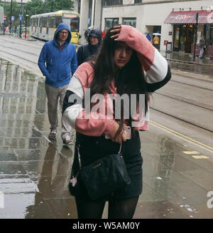 Manchester, Großbritannien. 27. Juli, 2019. Eine Frau, die Schutz bei starkem Regen auf dem Petersplatz Credit: Ioannis Alexopoulos/Alamy leben Nachrichten Stockfoto