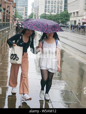 Manchester, Großbritannien. 27. Juli, 2019. Zwei Frauen halten einen Schirm bei starkem Regen auf dem Petersplatz Credit: Ioannis Alexopoulos/Alamy leben Nachrichten Stockfoto