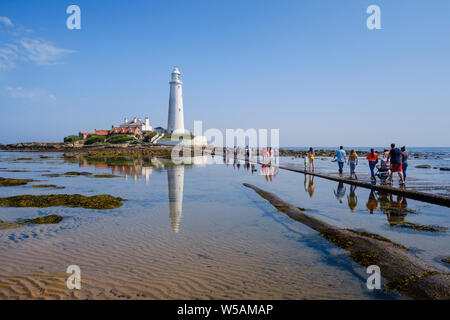 Auf der Northumberland Küste - tagestouristen Touristen und Familien zu Fuß über den Damm zu St Mary's Leuchtturm in Whitley Bay North Tyneside Stockfoto