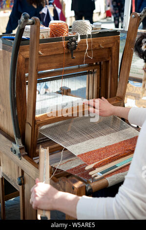 Nähe zu Händen von Frau Weberei Farbe Muster auf traditionelle Weberei Holz- Webstuhl. Stockfoto