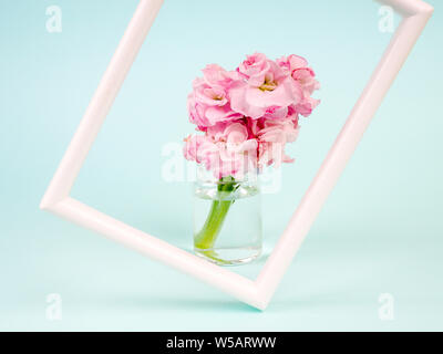 Weiße Landschaft frame Mockup gestaltete Vase mit Blumen in der Nähe der blauen Wand. Leeren Rahmen mock up für Presentation Design. Vorlage framing für moderne Kunst Stockfoto