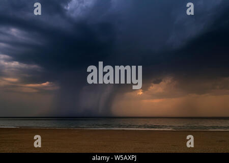 Gewitter, dunkle Regenwolken und Wolkenbruch/Sprühflutanlage über das Meer während der Hitzewelle/Hitzewelle im Sommer Stockfoto