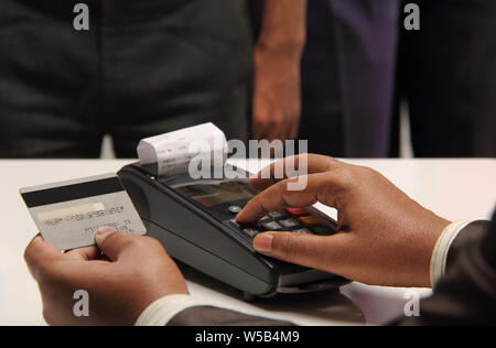 Shop-Assistent, der die PIN der Kreditkarte über die Maschine eingibt Stockfoto