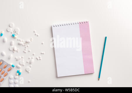 Medikamente, Bleistift und Notizbuch auf weißem Hintergrund. Medizinisches Konzept. Flach. Stockfoto