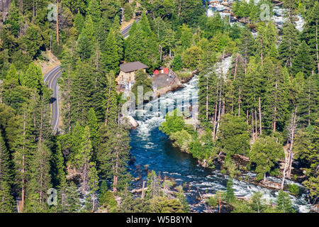 Luftaufnahme von Merced River fließt durch einen Nadelwald; electric power station und gepflasterte Straße sichtbar auf der linken Seite, Yosemite National Park, Ca Stockfoto