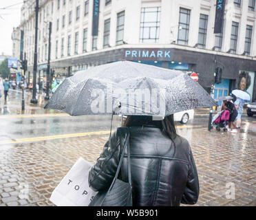 Manchester, Großbritannien. 27. Juli, 2019. Eine Frau mit einem Regenschirm bei starkem Regen in Manchester. Credit: Yiannis Alexopoulos/SOPA Images/ZUMA Draht/Alamy leben Nachrichten Stockfoto