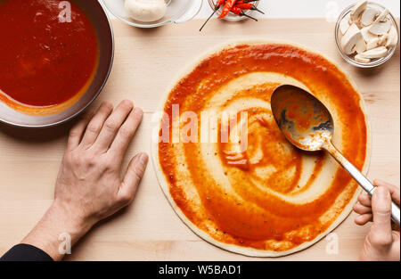 Chef Cooking Pizza, Verbreitung Tomatensauce auf Pizza base Stockfoto