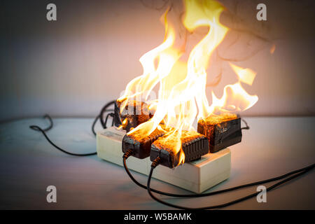 Auf Feuer Adapter an der Steckdose auf weißem Hintergrund, Elektrischer Kurzschluss Fehler in Strom Kabel resultierende verbrannt Stockfoto