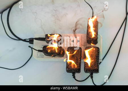 Auf Feuer Adapter an der Steckdose auf weißem Hintergrund, Elektrischer Kurzschluss Fehler in Strom Kabel resultierende verbrannt Stockfoto