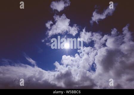 Sonne in der Mitte der Wolken im Dunkeln Blauer Himmel Stockfoto