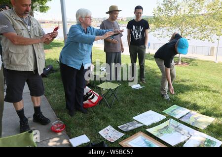 Cincinnati, Ohio, USA. 27. Juli 2019. (190727) - CINCINNATI (USA), 27. Juli 2019 (Xinhua) - Jan Braun Checco (2 l), Lead Artist von Cincinnati/Liuzhou Paint Programm, nimmt Bilder der Zeichnungen mit Ihrem Handy, an der Smale Riverfront Park in Cincinnati, Ohio, USA, 25. Juli 2019. Chinesische und US-amerikanische Künstler vor kurzem nahmen an der Cincinnati/Liuzhou Paint Programm, in dem sich Künstlerinnen aus dem Süden Chinas Autonomen Region Guangxi Zhuang wurden eingeladen, Cincinnati für eine Woche zu besuchen. Quelle: Xinhua/Alamy leben Nachrichten Stockfoto