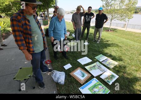 Cincinnati, Ohio, USA. 27. Juli 2019. (190727) - CINCINNATI (USA), 27. Juli 2019 (Xinhua) - Jan Braun Checco (2 l), Lead Artist von Cincinnati/Liuzhou Paint Programm, Blick die Zeichnungen von chinesischen Künstlern, Smale Riverfront Park in Cincinnati, Ohio, USA, 25. Juli 2019. Chinesische und US-amerikanische Künstler vor kurzem nahmen an der Cincinnati/Liuzhou Paint Programm, in dem sich Künstlerinnen aus dem Süden Chinas Autonomen Region Guangxi Zhuang wurden eingeladen, Cincinnati für eine Woche zu besuchen. Sie besuchten Museen und Galerien, ausgetauschte Kunst Ansichten und Techniken mit ihren US-Kredit Stockfoto