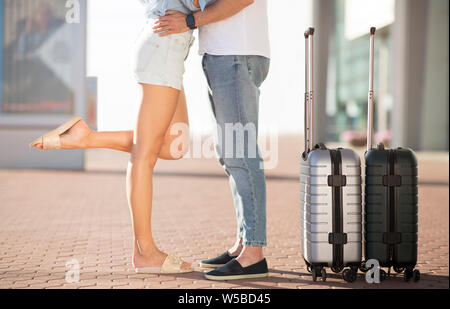 Paar in Flughafen küssen, stehend im Freien mit Gepäck Stockfoto