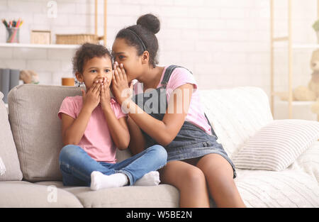 Ältere und kleine Schwestern sprechen zu Hause zu Hause über Geheimnisse Stockfoto