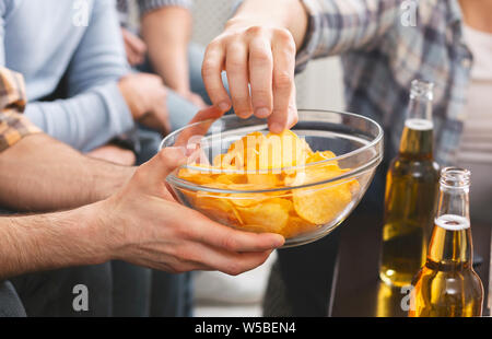 Mann hält Schüssel mit Chips mit Freunden auf einer Party Stockfoto