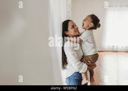 Seitenansicht der jungen Mutter mit Kleinkind Junge in Umarmung im Studio Stockfoto