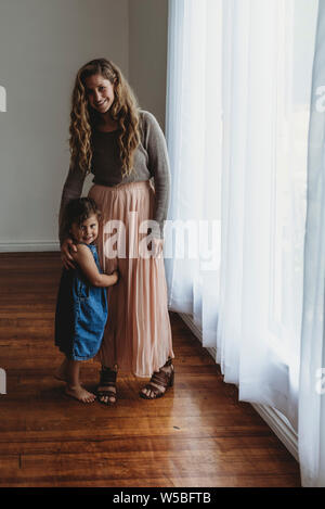 Volle Länge Portrait von Mutter und Tochter lächelnd an der Kamera in Studi Stockfoto