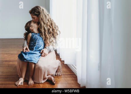 Vollständige Ansicht der Mutter küssen Tochter auf die Stirn, während Sie die Hände Stockfoto