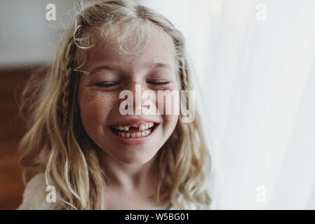 Porträt der jungen Sommersprossige lächelnde Mädchen fehlenden Zahn mit geschlossenen Augen Stockfoto