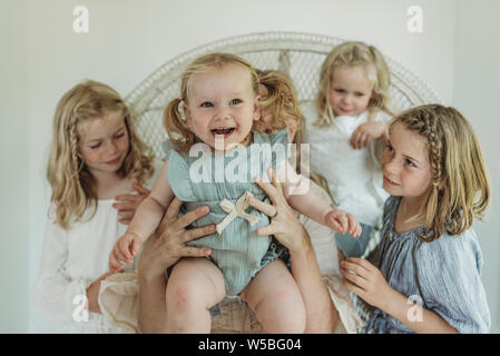 Ein Jahr altes Mädchen durch die Mutter mit Schwestern auf, Stockfoto