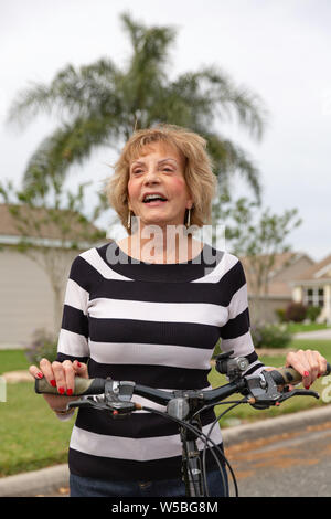 Reife Frau in ihrem 70er lachend auf ihr Fahrrad. Stockfoto