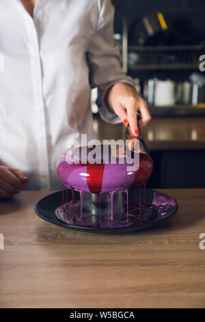 Women's Hände, die Spachtel und glättende Creme auf einem Kuchen. Stockfoto