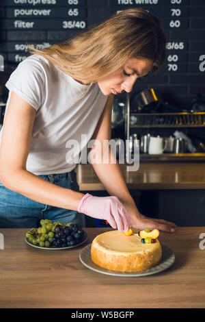 Junge und schöne Mädchen im weißen T-Shirt und rosa Handschuh dekorieren Kuchen Stockfoto