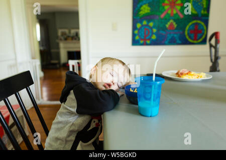 Müde toddler Boy einschläft, während im Esszimmer Stuhl Stockfoto