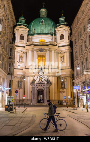 Mann mit einem Fahrrad vor der St. Peter Katholische Kirche geht. Der St. Peter's, Peterskirche in Österreich, ist eine Barocke römisch-katholisch. Stockfoto