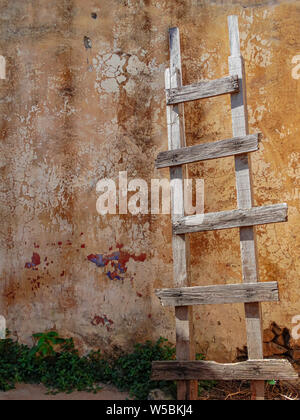 Wheathered rustikale Holztreppe, auf einem gelben im Alter von Zement Wand, mit Sonnenlicht Stockfoto