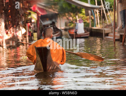 Eine traditionelle buddhistische Monkin einem Einbaum in der sehr beliebten Damnoen Saduak Markt in der Nähe von Bangkok, Thailand, in Asien eine wichtige touristische Destinat Stockfoto