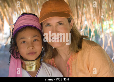 Frauen mittleren Alters Touristt amd einen traditionellen Long Neck Karen Hill Tribe junges Mädchen in Chiang Rei in Thailand mit Blick auf die Kamera Touristische freigegeben wird. Stockfoto