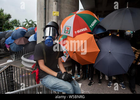 Anti Regierung Demonstranten gesehen mit Gasmasken und Sonnenschirmen ausgestattet, um sich vor möglichen Gas und Pfefferspray Nutzung Tränengas durch die Polizei während der Demonstration zu schützen. Tausende von demonstrant weiterhin ihren wöchentlichen Protest gegen die Regierung fordert die Regierung die Auslieferung Rechnung vollständig zu Rückzug und eine unabhängige Kommission in die Fragen der Polizei Einsatz unverhältnismäßiger Gewalt gegen Demonstranten zu schauen und die Verknüpfung mit lokalen Bandenmitglieder Demonstranten in der vergangenen Woche in Angriff zu nehmen. Der Protest fand im Yuen Long Bezirk, wo die Demonstranten brutal Attacke waren Stockfoto