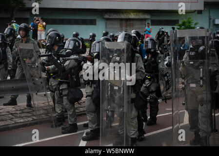 Riot Polizisten vorbereiten zum Feuer Tränengaskanister auf die Demonstranten reißen. Tausende von demonstrant weiterhin ihren wöchentlichen Protest gegen die Regierung fordert die Regierung die Auslieferung Rechnung vollständig zu Rückzug und eine unabhängige Kommission in die Fragen der Polizei Einsatz unverhältnismäßiger Gewalt gegen Demonstranten zu schauen und die Verknüpfung mit lokalen Bandenmitglieder Demonstranten in der vergangenen Woche in Angriff zu nehmen. Der Protest fand im Yuen Long Bezirk, wo die Demonstranten brutal von einem Mob von Gang-mitgliedern angegriffen wurden letzte Woche in Weiß gekleidet. Stockfoto