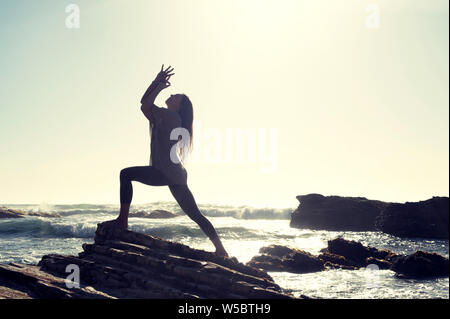 Die Frau, die durch das Meer mit ihren Armen in der yoga Eagle wickeln. Stockfoto