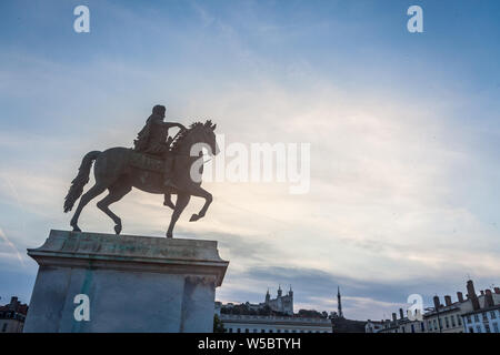 Roi Louis XIV Statue auf Anzeige auf dem Place Bellecour Square, in der Innenstadt von Lyon, Frankreich, mit der Basilika Notre Dame De Fourviere Kirche in backgrou Stockfoto