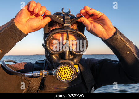 Eine wilde Oyster Diver bereitet und prüft seine Ausrüstung vor dem Tauchgang, Wittman, Maryland. Stockfoto