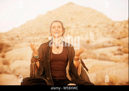 Schamane Frau arbeiten mit Raven und Hawk feather totem Energie in Joshua Tree, Kalifornien, USA Stockfoto