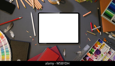 Overhead shot von Artist's Studio mit leerer Bildschirm Tablet mit Malerei Werkzeuge und Schreibwaren auf dunklem Hintergrund Stockfoto