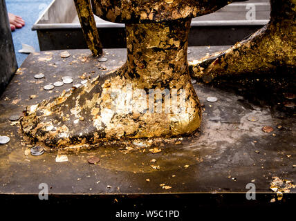 Golden Leaf aufgezeichnet und Thai Badewanne Münze auf den Fuß Buddha Statue Stockfoto