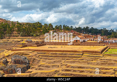 Landwirtschaftlichen Terrassen in der Inka Ruine von Chinchero mit unkenntlich Touristen und Kolonialstil Stadtzentrum mit Kirche, Cusco Region, Peru. Stockfoto