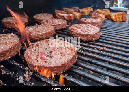 Hamburger und Lammkoteletts kochen auf einem heißen Grill im Freien Gass Stockfoto