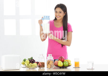 Porträt einer Frau hält einen Krug Milch und lächelnd Stockfoto