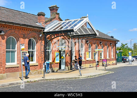 Menschen außerhalb Ormskirk Merseyrail viktorianisch aufgeführten alten öffentliche Verkehrsmittel Bahnhof Bauen & Bushaltestelle in gepflasterten Straße Lancashire England Großbritannien Stockfoto