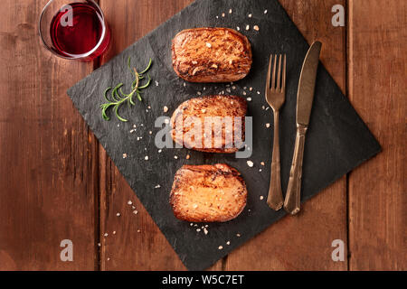 Rumpsteak Rindfleisch Steaks mit Salz, Rosmarin, und Rotwein, geschossen von oben auf einem schwarzen Schiefer Platte Stockfoto
