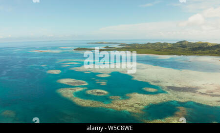 Inseln sind von einem Atoll und ein Korallenriff mit blauen Wasser der Ansicht von oben umgeben. Bucas Grande, Philippinen. Sommer und Reisen Urlaub Konzept. Stockfoto