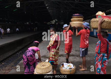 Torhüter in Chhatrapati Shivaji Maharaj Terminus (Csmt) in Mumbai, Indien, die Körbe mit Fischen auf dem Kopf einen ankommenden Zug zu liefern Stockfoto