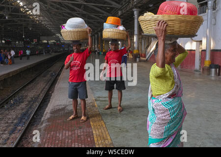 Torhüter in Chhatrapati Shivaji Maharaj Terminus (Csmt) in Mumbai, Indien, die Körbe mit Fischen auf dem Kopf einen ankommenden Zug zu liefern Stockfoto